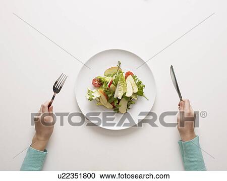 Stock Image - Hands by a plate of salad. Fotosearch