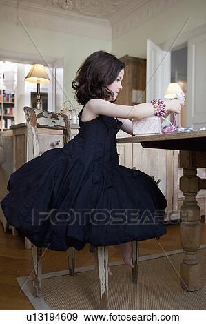 Stock Photo - little girl in dress on chair. Fotosearch