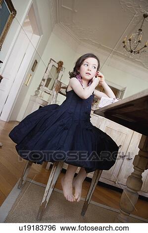 little girl in dress sitting on a chair View Large Photo Image Stock Photograph - little girl in dress sitting on a chair. Fotosearch