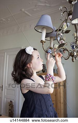 Picture - little girl touching chandelier. Fotosearch