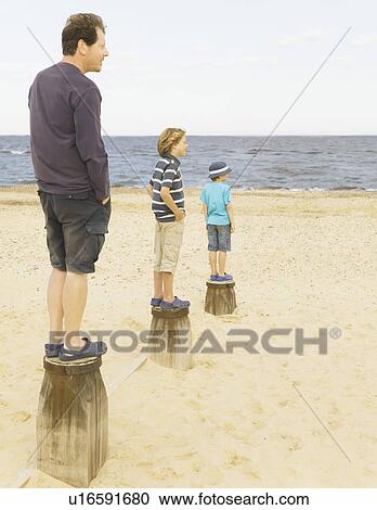 Man and children standing on groynes View Large Photo Image Stock Image - Man and children standing on groynes. Fotosearch