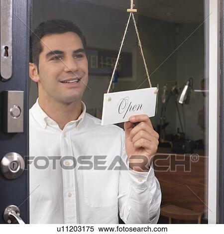 Stock Photography - man at door saying 'open'. Fotosearch