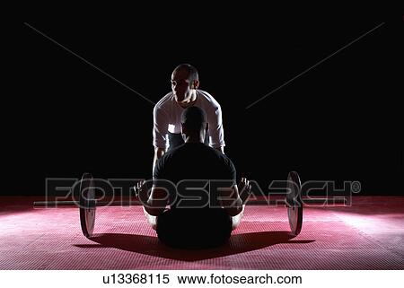 Stock Photography - man being helped up with weights bar. Fotosearch