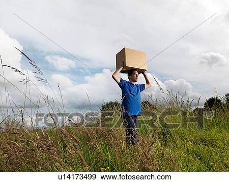 Stock Photo - man carrying boxes through field. Fotosearch