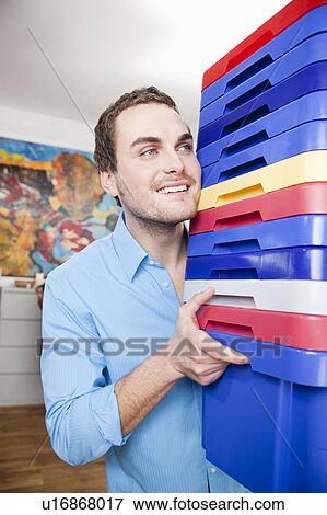 Stock Photo - man carrying colored boxes. Fotosearch