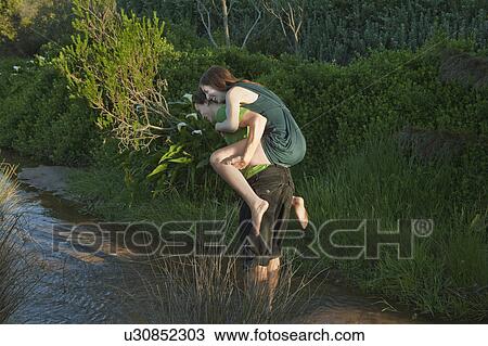 Man carrying girl on back through stream View Large Photo Image Stock Image - Man carrying girl on back through stream. Fotosearch