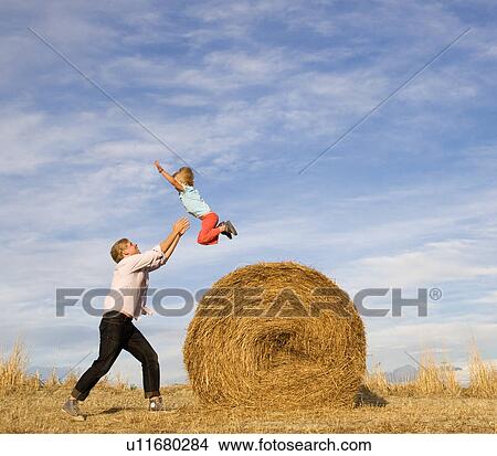 man catching boy jumping from hay bale View Large Photo Image Picture - man catching boy jumping from hay bale. Fotosearch