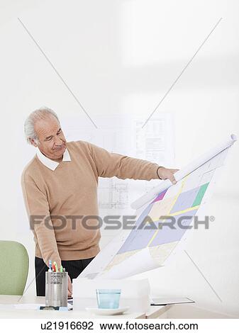 Man checking plan in an office View Large Photo Image Stock Image - Man checking plan in an office. Fotosearch