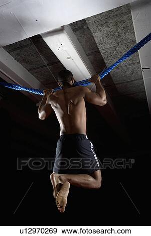 Stock Photo - man doing chin ups on rope. Fotosearch