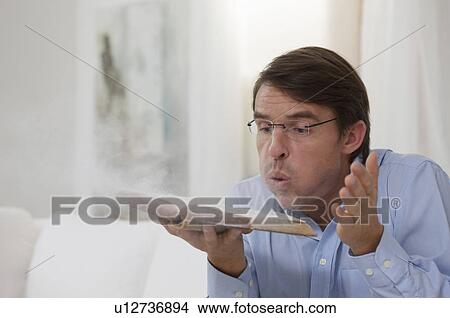 Picture - man dusting a book. Fotosearch
