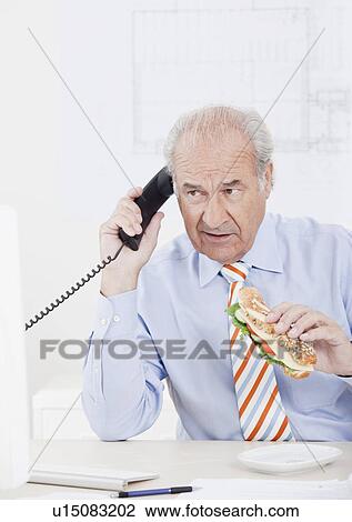 Man eating while on the phone View Large Photo Image Stock Image - Man eating while on the phone. Fotosearch