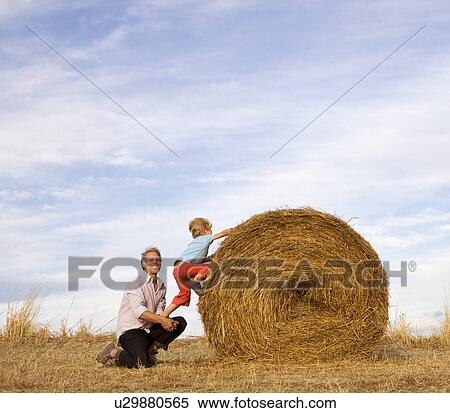man helping boy to climb hay bale View Large Photo Image Stock Photography - man helping boy to climb hay bale. Fotosearch