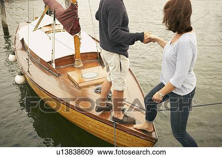 Man helping woman onto old boat View Large Photo Image Stock Photo - Man helping woman onto old boat. Fotosearch