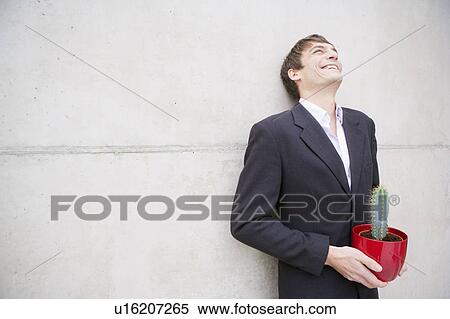 Stock Photography - man in suit holding a cactus. Fotosearch