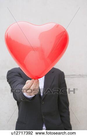 Stock Image - man in suit holding a heart balloon. Fotosearch