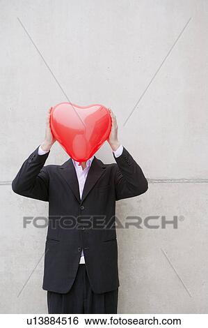 man in suit holding a heart balloon View Large Photo Image Stock Photograph - man in suit holding a heart balloon. Fotosearch