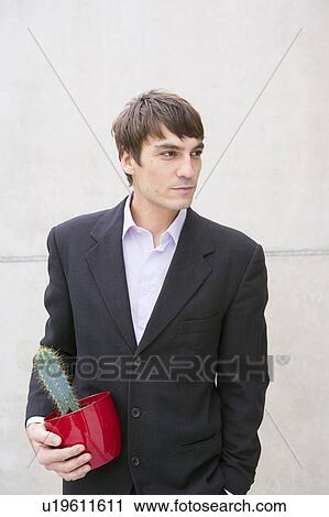 Stock Image - man in suit holding cactus. Fotosearch