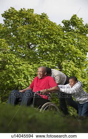 man in wheelchair pushed by children View Large Photo Image Picture - man in wheelchair pushed by children. Fotosearch