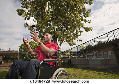 Stock Photo - man in wheelchair with ball. Fotosearch