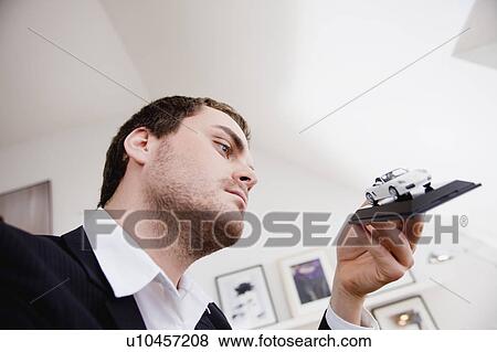 Stock Photo - man inspecting toy car model. Fotosearch
