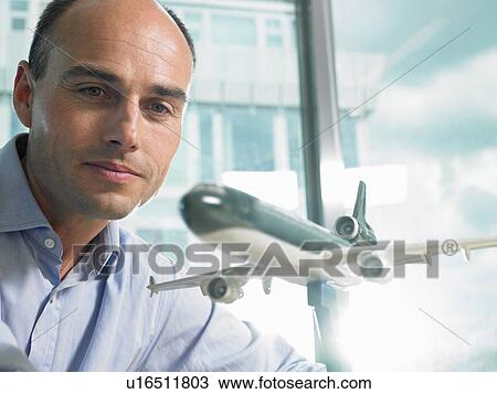 Stock Image - Man looking at a reduced plane model. Fotosearch