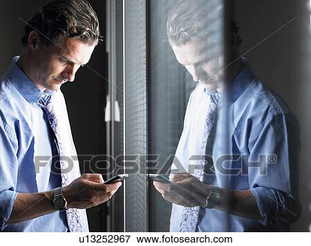 Man looking at his cellphone View Large Photo Image Stock Photo - Man looking at his cellphone. Fotosearch