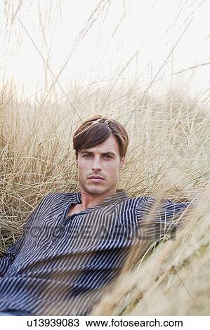 Stock Image - man lying in reed looking at viewer. Fotosearch