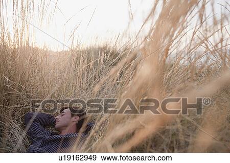 Stock Photo - man lying in reed sleeping. Fotosearch
