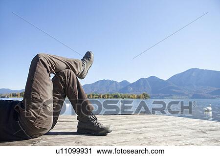 Stock Image - Man lying on a jetty. Fotosearch