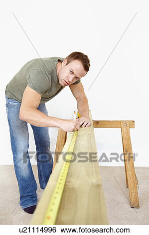Man measuring wooden plank View Large Photo Image Stock Photograph - Man measuring wooden plank. Fotosearch