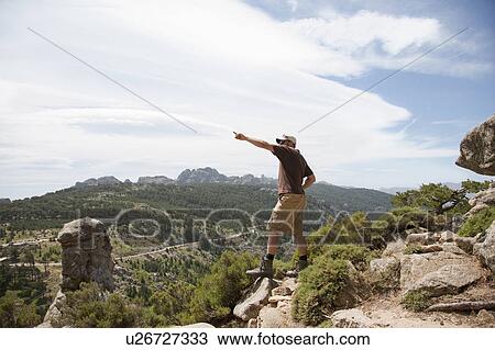 Stock Image - Man on a cliff pointing. Fotosearch