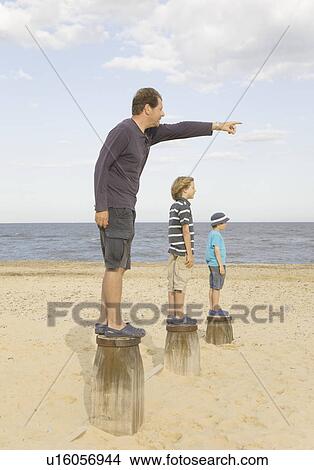 Picture - Man pointing with children on groynes. Fotosearch