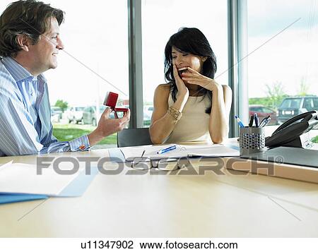 Man proposing to woman, at work View Large Photo Image Stock Image - Man proposing to woman, at work. Fotosearch