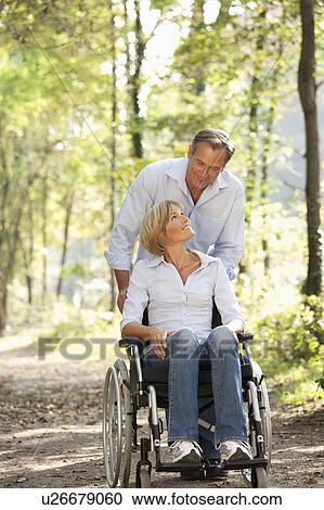 Man pushes woman in a wheelchair View Large Photo Image Stock Image - Man pushes woman in a wheelchair. Fotosearch