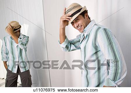 Stock Photography - Man putting on hat. Fotosearch