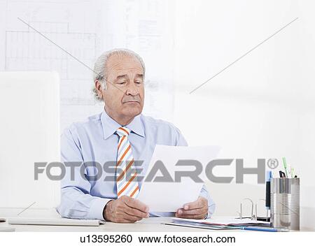 Man reading a paper in the office View Large Photo Image Stock Image - Man reading a paper in the office. Fotosearch