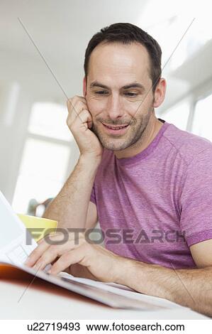 man sitting at table reading brochure View Large Photo Image Stock Image - man sitting at table reading brochure. Fotosearch