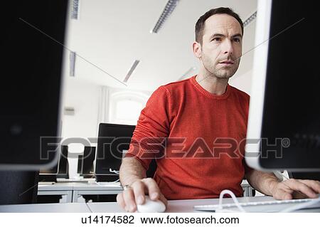 Stock Image - man sitting at terminal in lecture hall. Fotosearch
