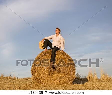 man sitting on hay bale View Large Photo Image Stock Photo - man sitting on hay bale. Fotosearch