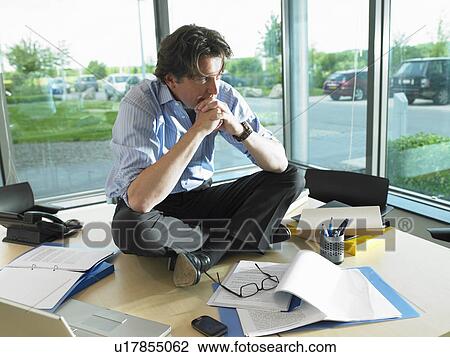 Man sitting on his desk, thinking View Large Photo Image Stock Image - Man sitting on his desk, thinking. Fotosearch