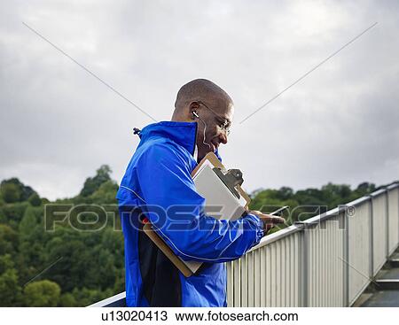 Stock Image - man talking on phone on walkway. Fotosearch