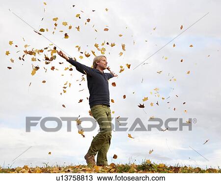 man walking through flying autumn leaves View Large Photo Image Stock Image - man walking through flying autumn leaves. Fotosearch