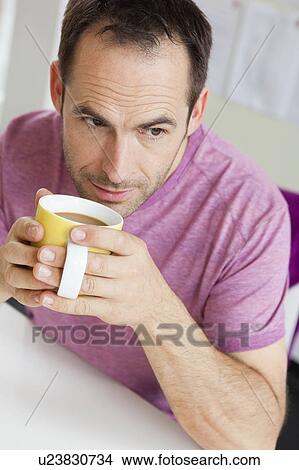 man with cup of coffee sitting at table View Large Photo Image Picture - man with cup of coffee sitting at table. Fotosearch