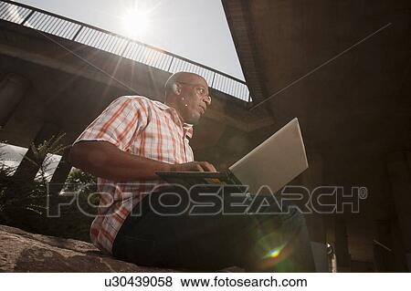 Stock Photo - man working on laptop in city. Fotosearch