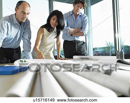 Stock Photo - Men and woman looking at blue prints. Fotosearch
