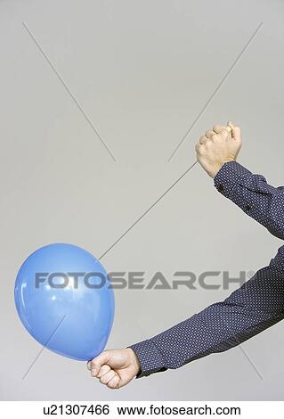 Stock Photograph - men's hands about to burst a balloon. Fotosearch