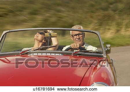 Picture - Mid aged couple in sports car. Fotosearch