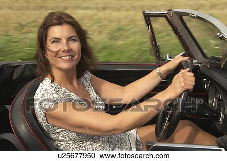 Stock Image - Mid aged woman in sports car. Fotosearch