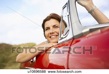 Stock Photo - Mid aged woman in sports car. Fotosearch