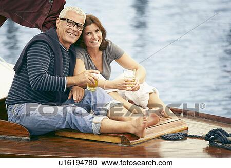 Stock Image - Middle aged couple drinking on boat. Fotosearch